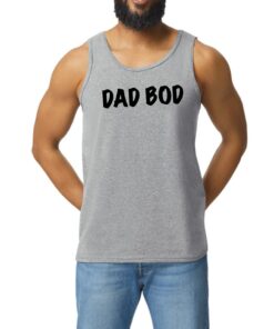A man with a beard and jeans is wearing a tank top.
