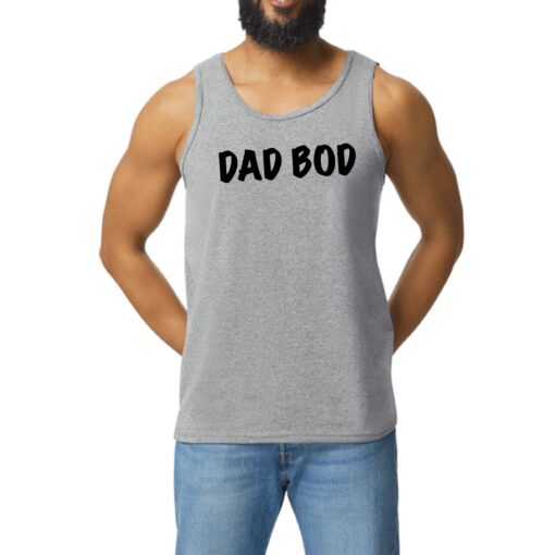 A man with a beard and jeans is wearing a tank top.